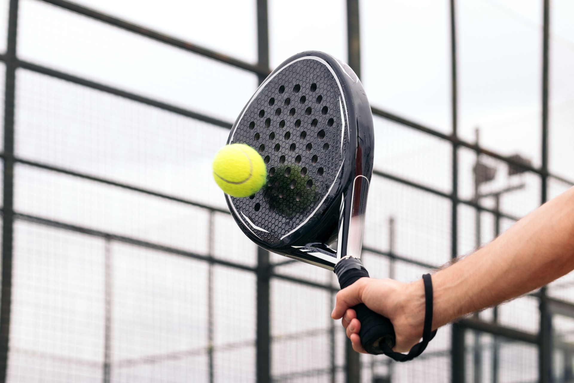 Paddle tennis racket striking a ball, close-up on the strings